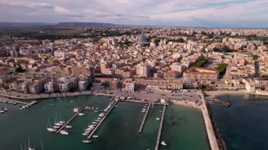 İtalya 'nın Syracuse şehrinde insansız hava aracıyla, mimari harikalarının, altın sahillerinin görkemli görüntüsünü yakalayacağız. Deniz yatlarla parıldıyor, zarif bir dans eşliğinde sularda zikzak çiziyor.