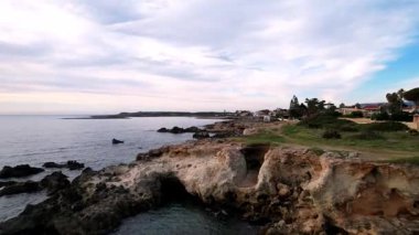 Sicilya 'daki Ognina Spiaggia di Punta Asparano' nun çarpıcı sahil şeridini keşfedin. Havadan bakıldığında kayalık kayalıklar, görkemli bir deniz kemeri ve kristal berrak sular görülüyor. Seyahat içeriği için ideal