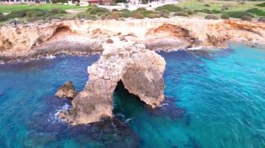 Sicilya 'daki Ognina Spiaggia di Punta Asparano' nun çarpıcı sahil şeridini keşfedin. Havadan bakıldığında kayalık kayalıklar, görkemli bir deniz kemeri ve kristal berrak sular görülüyor. Seyahat içeriği için ideal