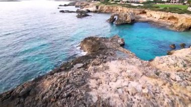 Sicilya 'daki Ognina Spiaggia di Punta Asparano' nun çarpıcı sahil şeridini keşfedin. Havadan bakıldığında kayalık kayalıklar, görkemli bir deniz kemeri ve kristal berrak sular görülüyor. Seyahat içeriği için ideal