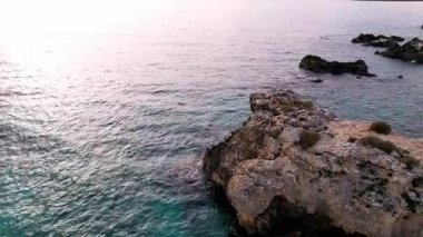 Sicilya 'lı Ognina Spiaggia di Punta Asparano' nun nefes kesici insansız hava aracı görüntüleri. Göz kamaştırıcı sahil uçurumlarının üzerinde süzülür, doğal kayalık kemer, parıldayan Akdeniz kıyıları. Seyahat ve doğa tutkunları için