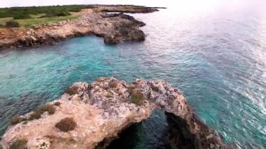 Sicilya 'lı Ognina Spiaggia di Punta Asparano' nun insansız hava aracı görüntüleriyle duyularınızı yükseltin. Engebeli uçurumlar, görkemli bir kemer ve sakin kıyı manzaraları. Cennetin mükemmel bir parçası
