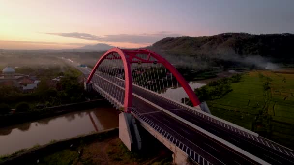 トランスジャワ有料道路 バタンの象徴的な赤い橋であるKalikuto橋の空中写真日の出 2022年11月12日インドネシア中部ジャワ — ストック動画