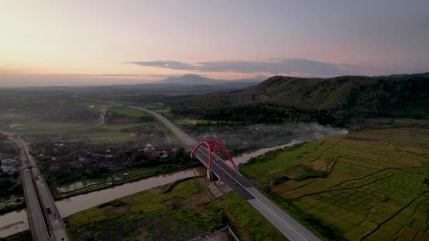 トランスジャワ有料道路 バタンの象徴的な赤い橋であるKalikuto橋の空中写真日の出 2022年11月15日インドネシア中部ジャワ — ストック動画