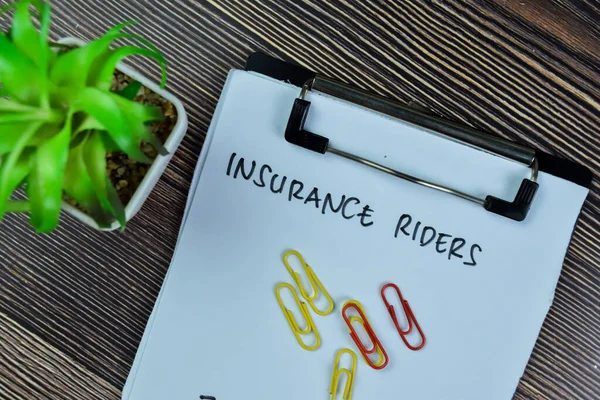 Concept of Insurance Riders write on paperwork isolated on Wooden Table.