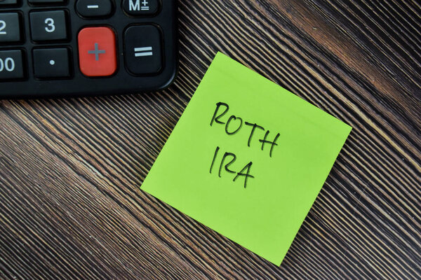 Concept of ROTH IRA write on sticky notes isolated on Wooden Table.