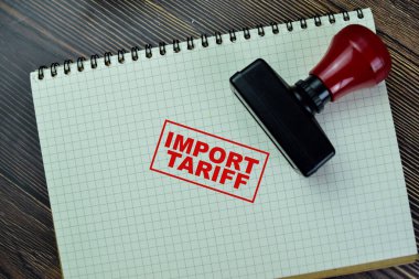 Concept of Red Handle Rubber Stamper and Import Tariff text isolated on on Wooden Table.