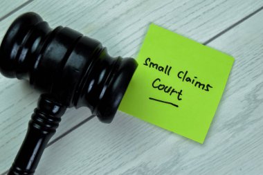 Concept of Small Claims Court write on sticky notes with gavel isolated on Wooden Table.