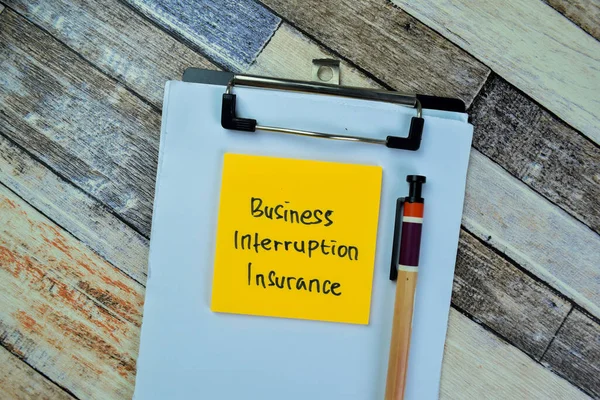 Concept of Business Interruption Insurance write on sticky notes isolated on Wooden Table.