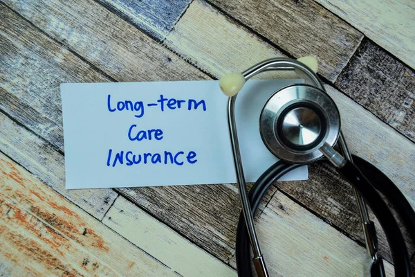 Concept of Long-Term Care Insurance write on sticky notes with stethoscope isolated on Wooden Table.
