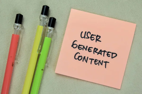 Concept of User Generated Content write on sticky notes isolated on Wooden Table.