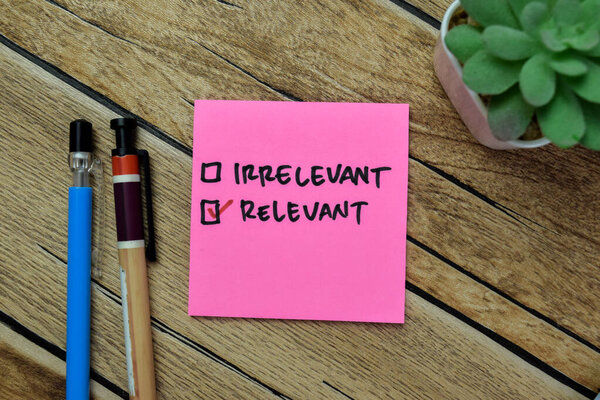 Концепция нерелевантного и релевантного письма на липких нотах, изолированных на деревянном столе.