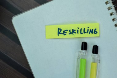 Concept of Reskilling write on sticky notes isolated on Wooden Table.