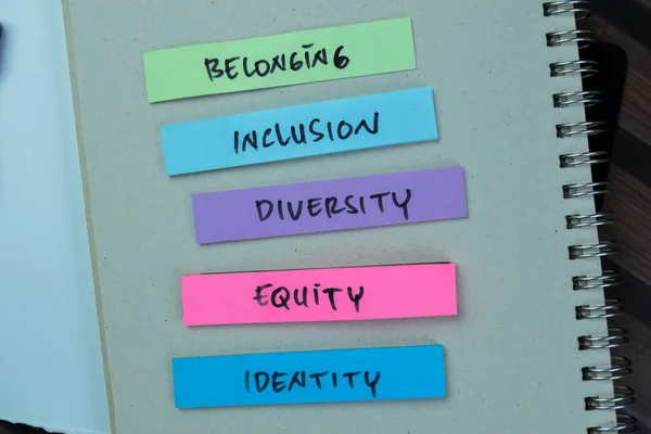 Concept of Belonging, Inclusion, Diversity, Equity, Identity write on sticky notes isolated on Wooden Table.