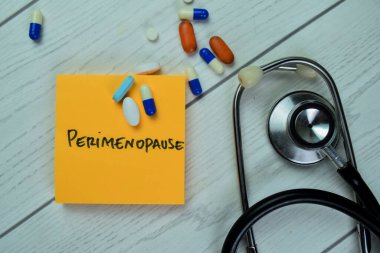Perimenopoz kavramı, ahşap masa üzerine izole edilmiş steteskop ile yapışkan notlara yazılır..