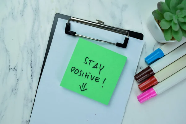 Concept of Stay Positive! write on sticky notes isolated on Wooden Table.