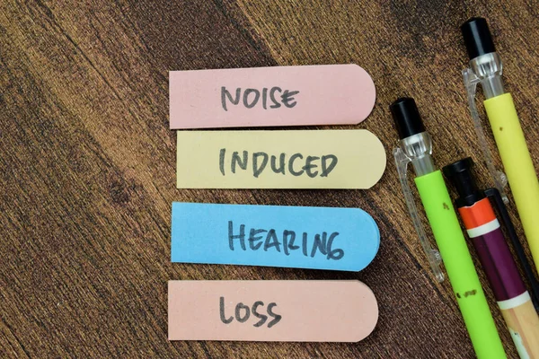 Concept of Noise Induced Hearing Loss write on sticky notes isolated on Wooden Table.