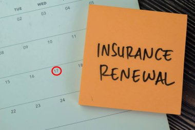Concept of Insurance Renewal write on sticky notes with calendar isolated on Wooden Table. clipart