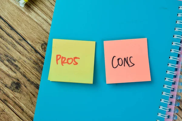 Concept of Pros or Cons write on sticky notes isolated on Wooden Table.