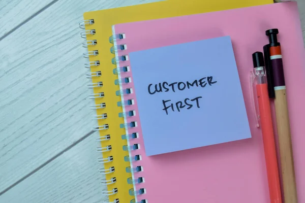 Concept of Customer First write on sticky notes isolated on Wooden Table.