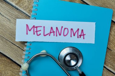 Melanoma kavramı, ahşap masa üzerine izole edilmiş steteskopla yapışkan notlara yazılır..