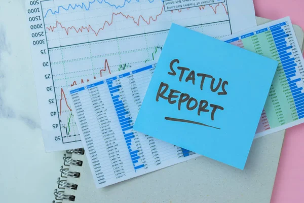 Concept of Status Report write on sticky notes isolated on Wooden Table.
