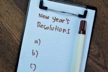 Yeni Yıl Kararları kavramı, Ahşap Masa 'da izole edilmiş ek hizmetlerin desteğiyle kağıt üzerinde yazıyor..