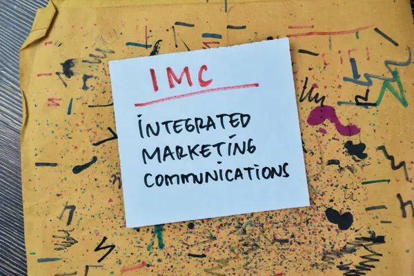 Concept of IMC - Integrated Marketing Communications write on sticky notes isolated on Wooden Table.