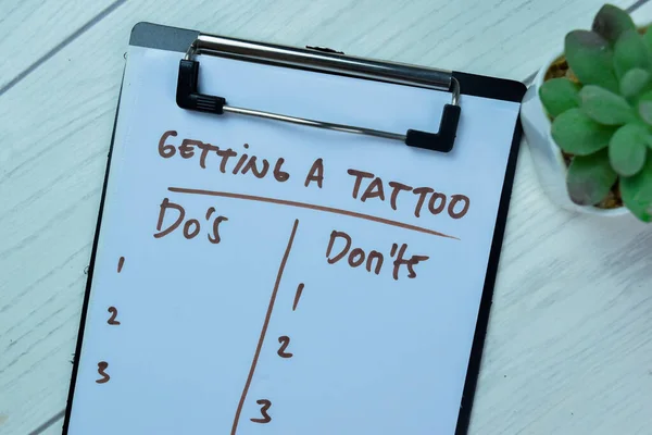 Concept of Getting A Tattoo with Do\'s and Don\'ts write on paperwork isolated on Wooden Table.