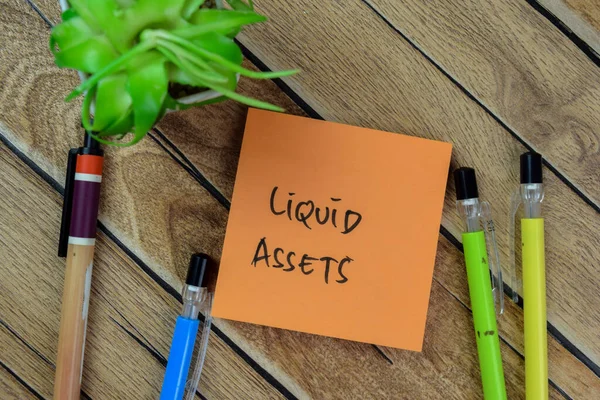Concept of Liquid Assets write on sticky notes isolated on Wooden Table.
