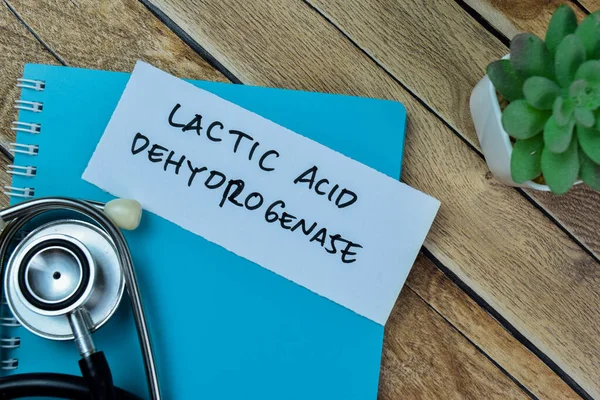 Concept of Lactic Acid Dehydrogenase write on sticky notes with stethoscope isolated on Wooden Table.