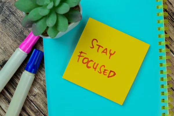 Concept of Stay Focused write on sticky notes isolated on Wooden Table.