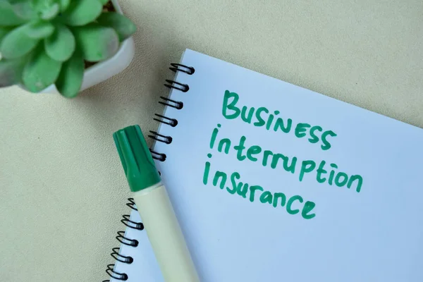 Concept of Business Interruption Insurance write on book isolated on Wooden Table.
