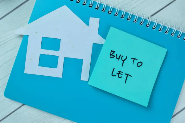 Concept of Buy To Let write on sticky notes isolated on Wooden Table.