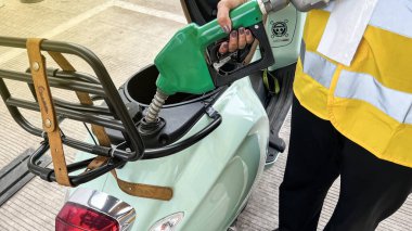 Benzin istasyonundaki işçiler müşterilerine benzin doldurmak için alıcının motosikletine benzin dolduruyorlar. Bekasi, Endonezya, 5 Aralık 2023
