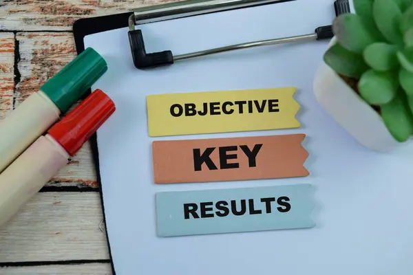 Concept of Objective Key Results write on sticky notes isolated on Wooden Table.