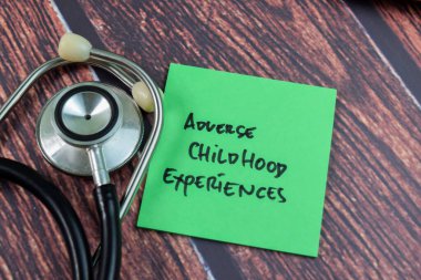 Kötü Çocukluk Deneyimleri kavramı yapışkan notlara yazılır ve steteskop tahta masa üzerinde izole edilir.