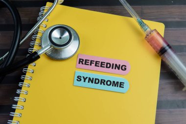 Yeniden Beslenme Sendromu kavramı yapışkan notlara yazılıyor ve steteskop tahta masa üzerinde izole ediliyor..
