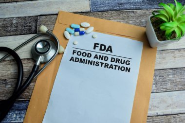 FDA kavramı - Gıda ve İlaç İdaresi, ahşap arka planda izole edilmiş evrak işleri üzerine yazılar yazdı.