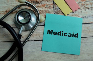 Medicaid kavramı, ahşap masa üzerine izole edilmiş steteskop ile yapışkan notlara yazılmıştır..