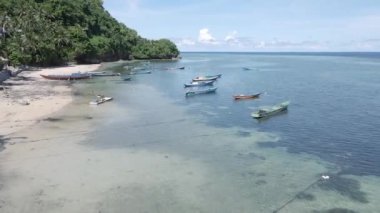 Motorlu teknelerin hava görüntüsü Run Island 'a demirli evlerin olduğu ahşap güvertede. Parlak mavi gökyüzü Maluku, Endonezya, 18 Nisan 2024