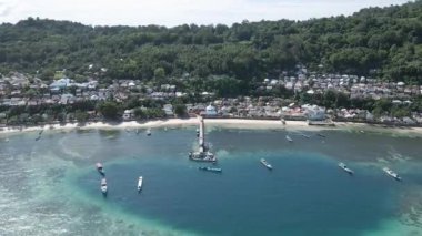Motorlu teknelerin hava görüntüsü Run Island 'a demirli evlerin olduğu ahşap güvertede. Parlak mavi gökyüzü Maluku, Endonezya, 18 Nisan 2024