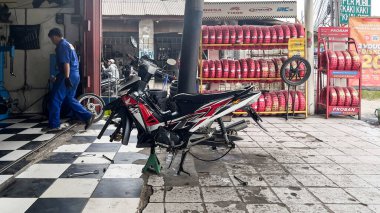 Tamirci atölyedeki alet kutusunun yanında motosiklet kontrolü yapıyor. Jakarta, Endonezya, 1 Mayıs 2024