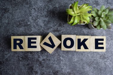 Concept of The wooden Cubes with the word Revoke on wooden background. clipart