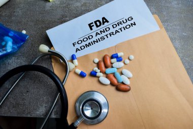 Kırmızı Saplı Lastik Stamper ve FDA - Kahverengi zarfın üzerindeki Gıda ve İlaç İdaresi metni Tahta arka planda izole edilmiş