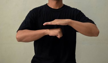 Gri arka planda işaret diliyle hareket eden genç adam