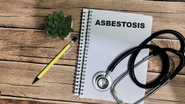 Concept of Asbestosis write on book isolated on Wooden Table. clipart