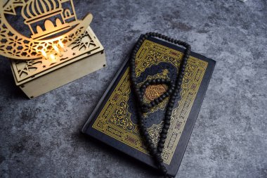 Kutsal Kur 'an, tespih, altın ramadhan lambası, koyu arkaplanda islami tespih boncukları. İslam kavramı