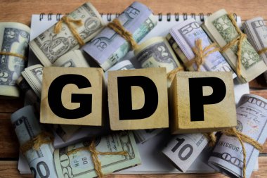 Tahta bir masadaki tahtadan bloklardaki GSYİH sözcüğünü ve dolar banknotlarını kabul et.