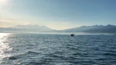 Denizin üzerinde sabahın erken saatlerinde gün doğumu. Bazı bulutlar.